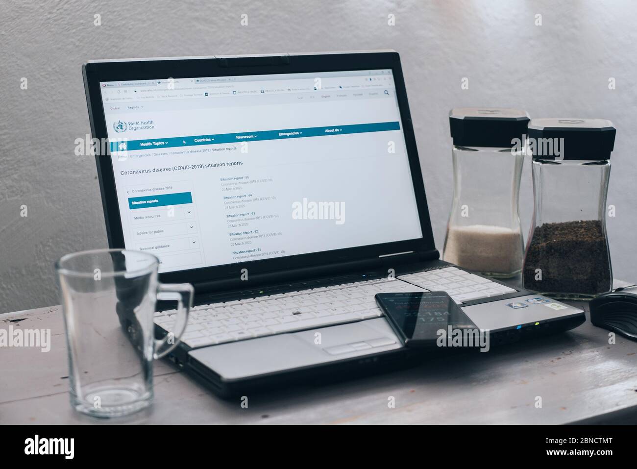 Laptop mit Website der Weltgesundheitsorganisation auf Seite der Coronavirus-Krankheit (Covid-19) Lagebericht, Notizbuch auf Holztisch mit Glas Kaffee und Tasse, Mexiko, 14. Mai 2020 Stockfoto