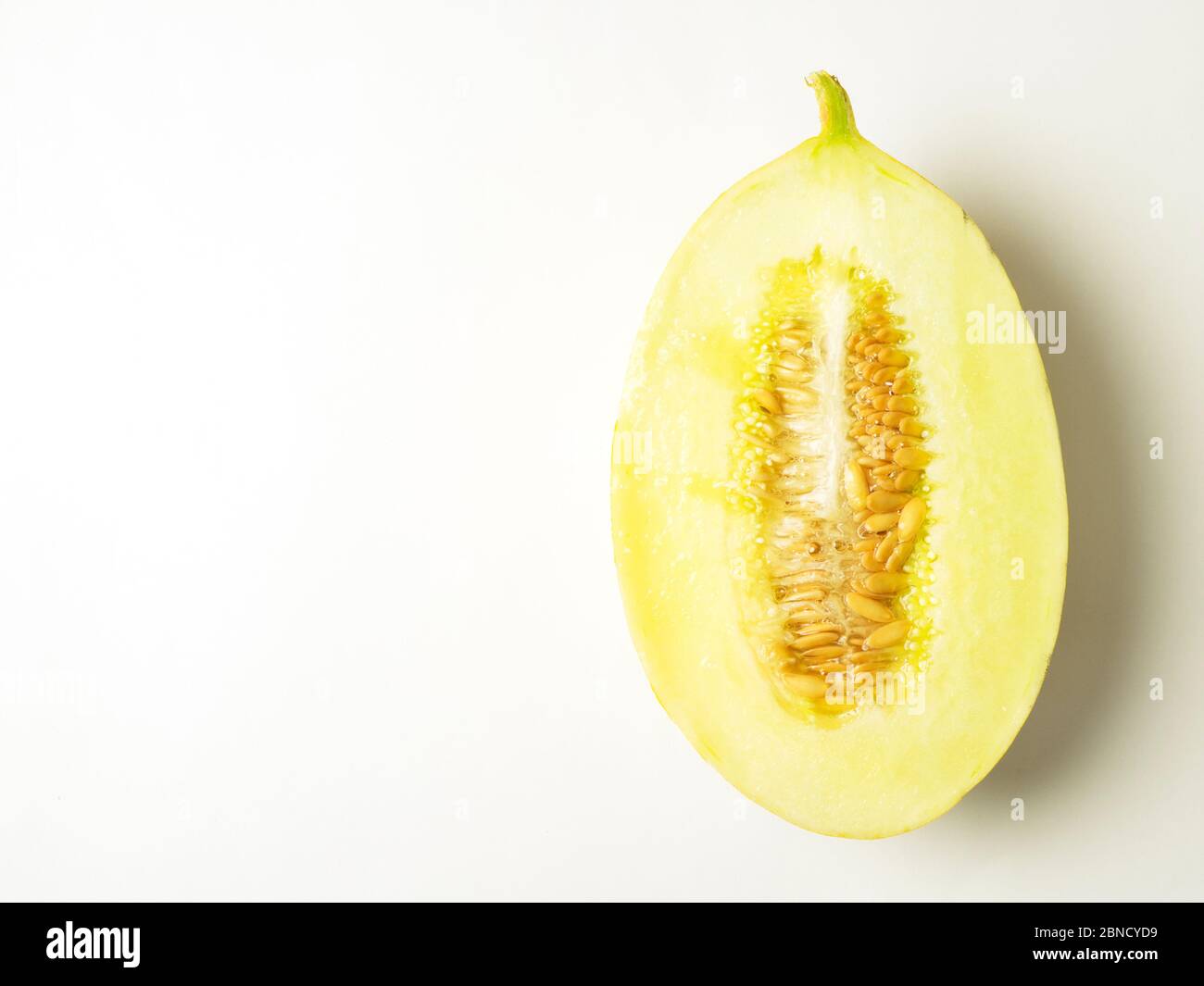 Eine halbe kanarienmelone mit Samen auf weißem Hintergrund mit Kopierraum Stockfoto