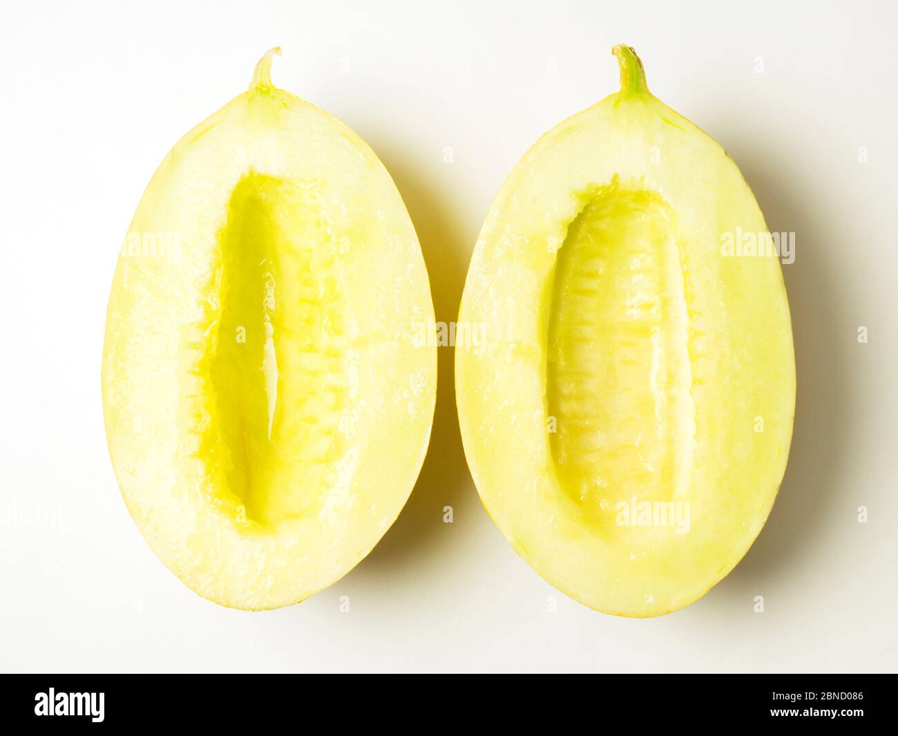 Zwei Hälften einer kanarienmelone eine ohne Samen auf weißem Hintergrund Stockfoto