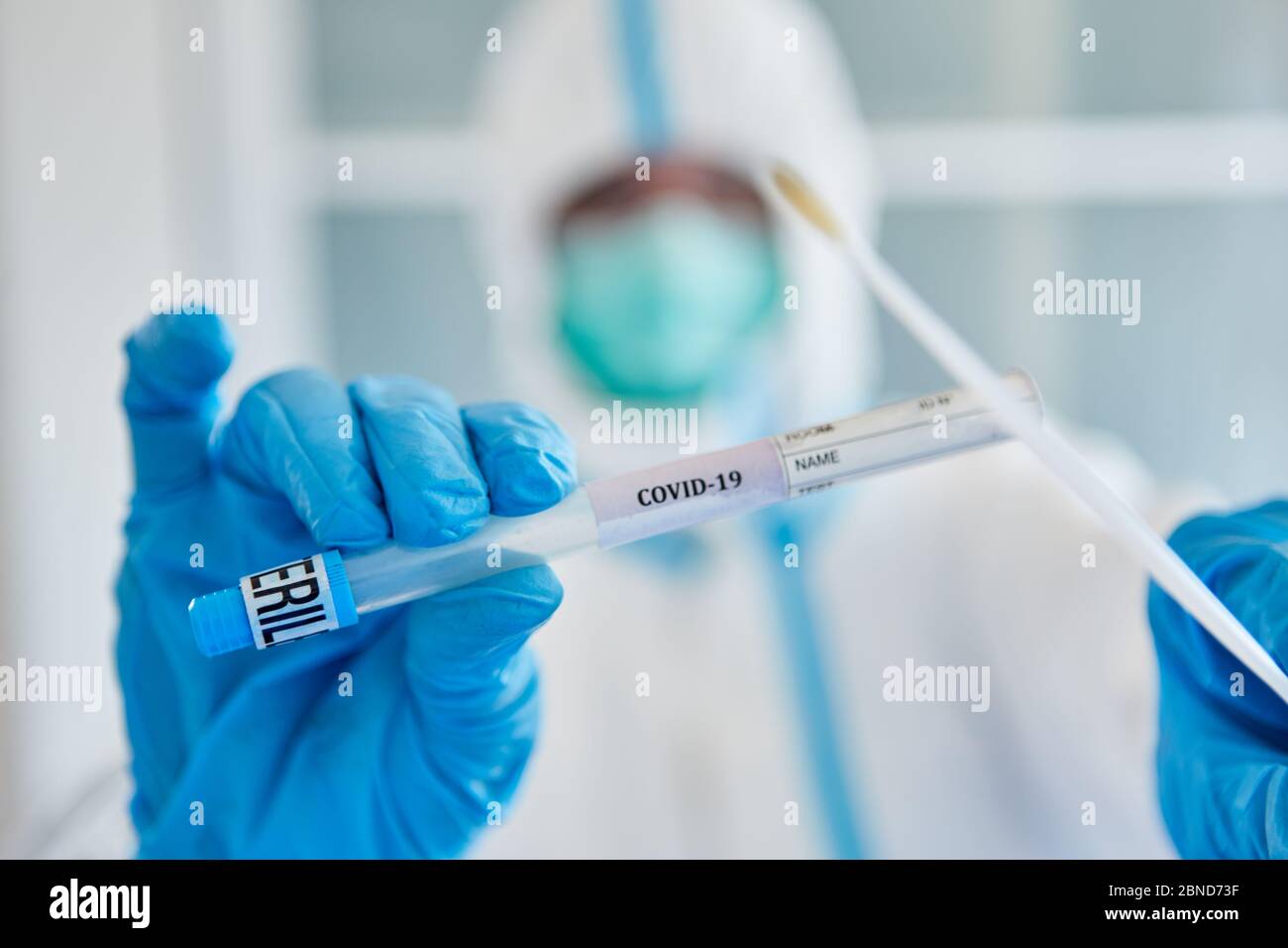 Medic in Schutzkleidung zeigt einen Rachenabstrich auf Speichelprobe für den Coronavirus-Test Stockfoto