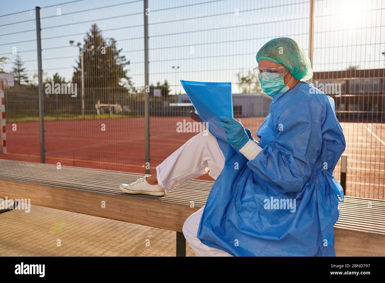 Mitarbeiter der Gesundheitsabteilung mit Dokumenten oder Kontaktauflistenvor dem Sportplatz während der Coronavirus-Pandemie Stockfoto