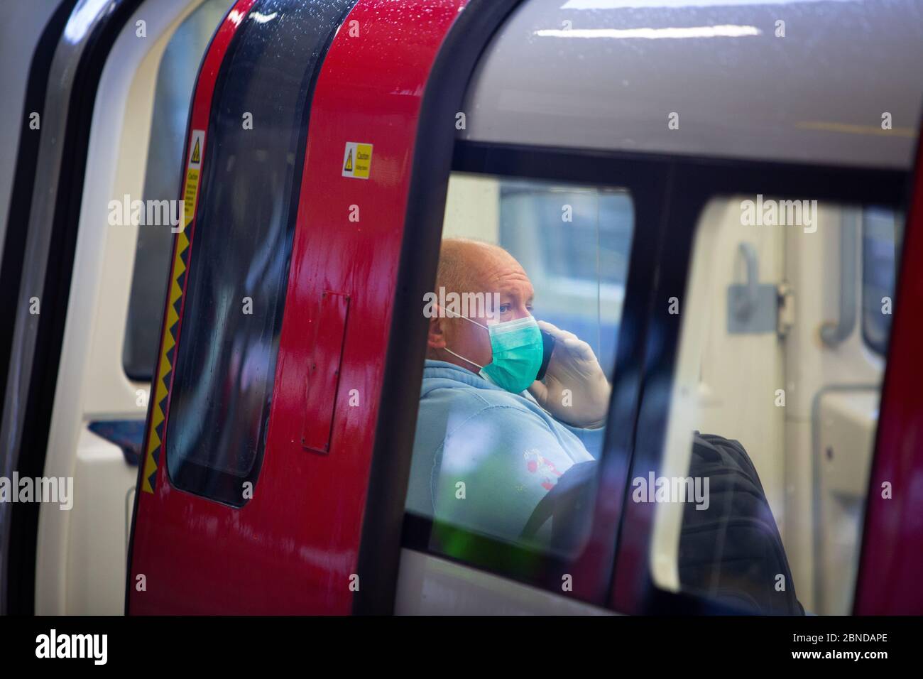 Die Gesichtsmaske sitzt während des COVID-19-Ausbruchs auf einer Londoner U-Bahn Stockfoto