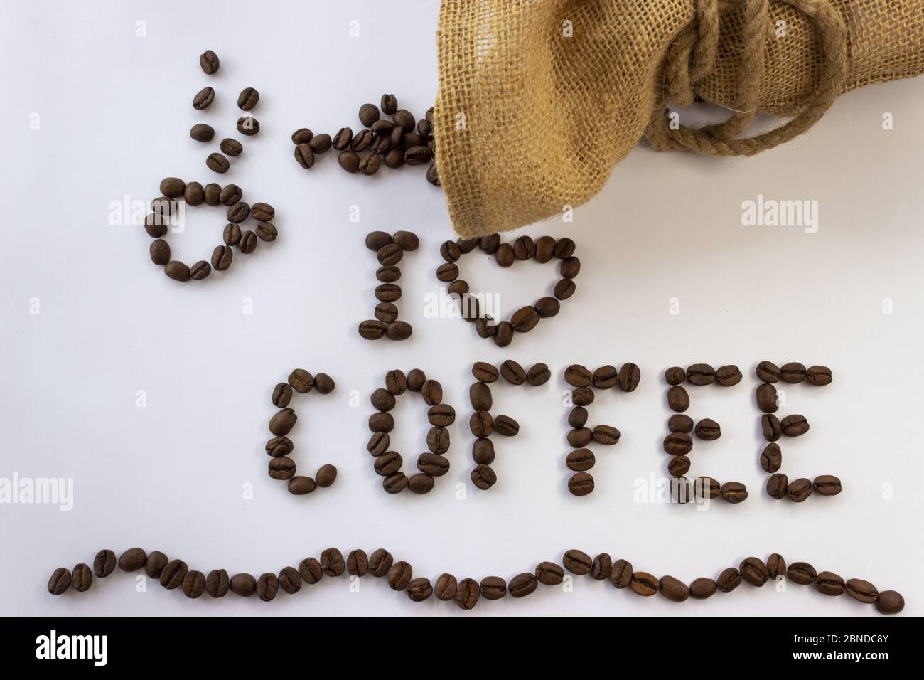 Inschrift ich liebe Kaffee aus Kaffeebohnen und Jute Beutel mit Kaffee mit Schnur gebunden und verschüttete Kaffeebohnen auf einem weißen Hintergrund Stockfoto