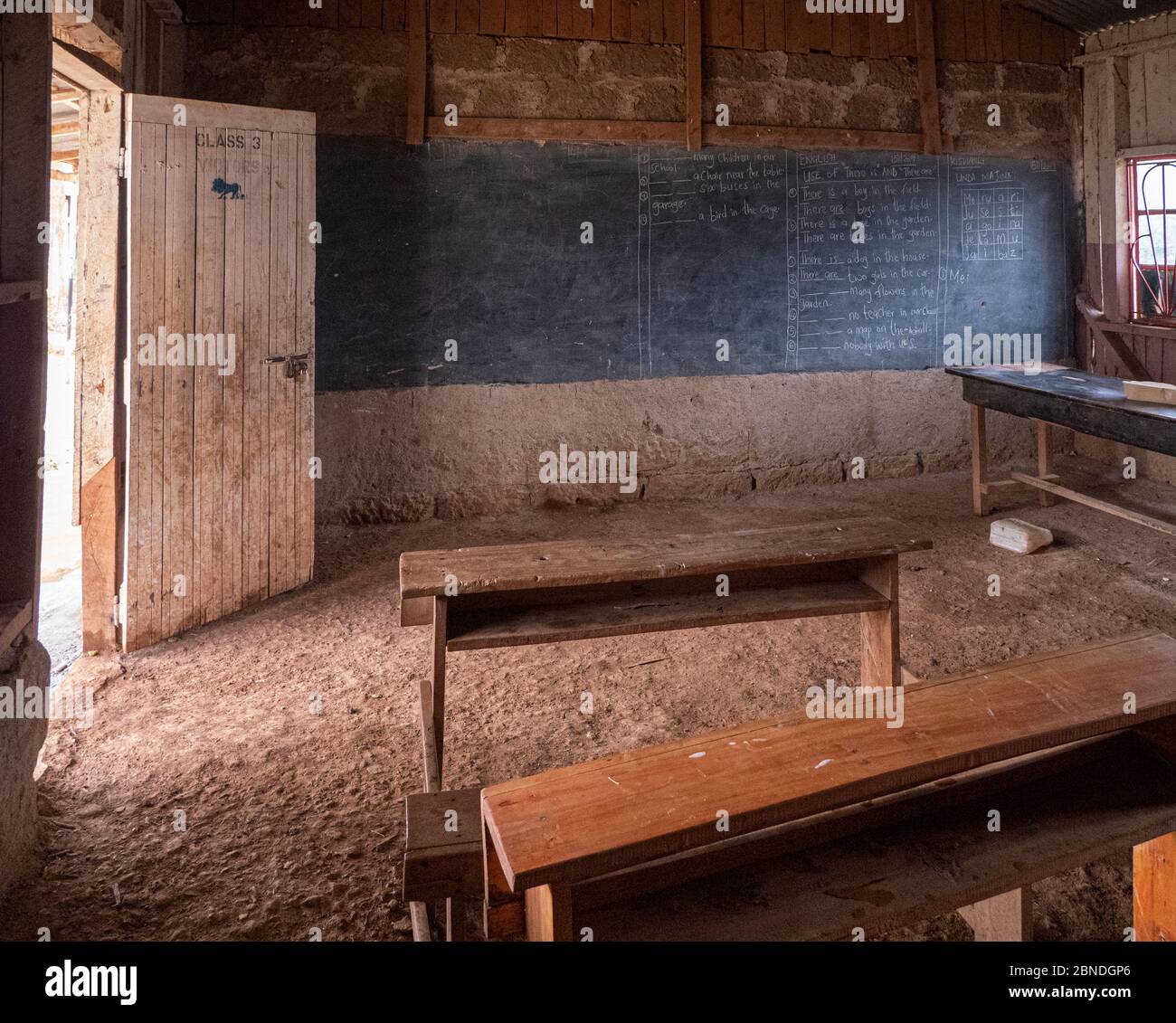 Typische arme Schule in Kenia mit dreckigem Boden und alten Holztischen Stockfoto