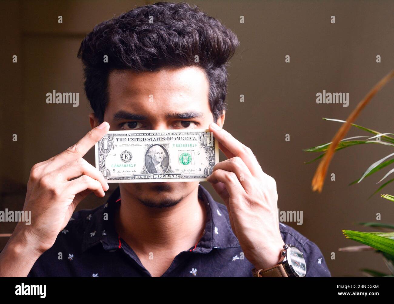 Junger Mann hält einen Dollar-Rechnung vor seinem Gesicht.ein Dollar.Konzept Vorderansicht Stockfoto