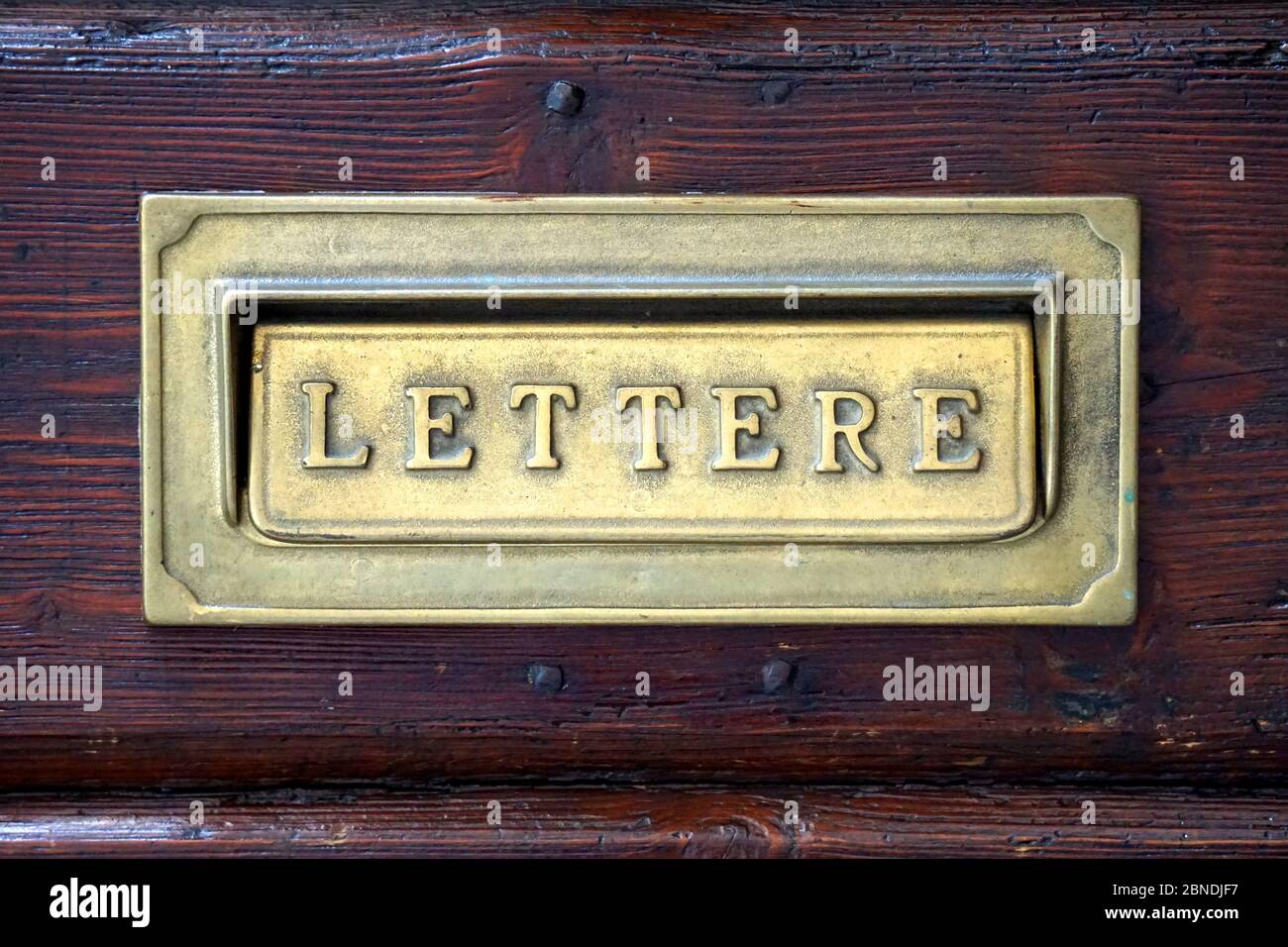 Italienischer Briefkasten in einer alten dunklen Tür. Stockfoto