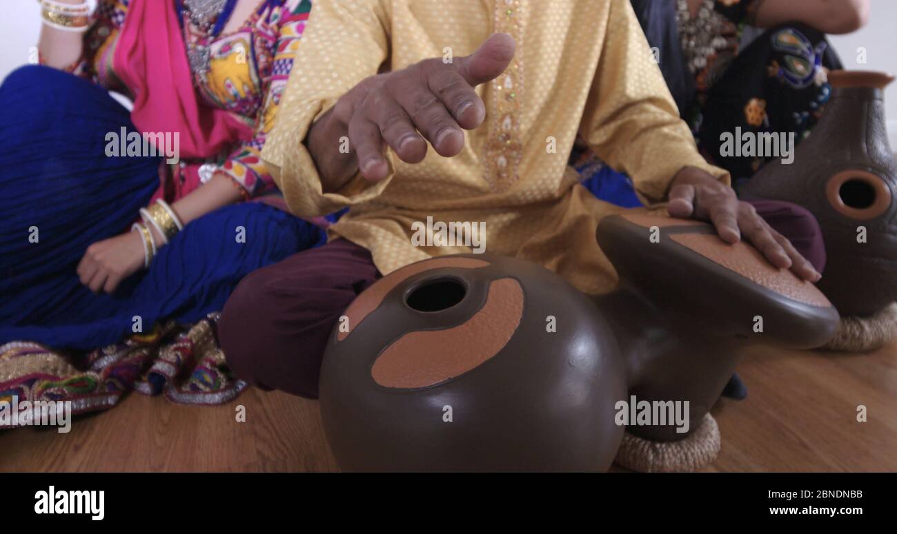 Mann spielt indische Trommeln mit Tänzerinnen. Stockfoto