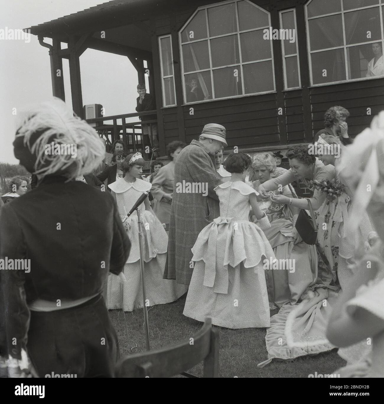 1950er Jahre, historisch, auf dem Rasen vor einem hölzernen Sportpavillion in Farnworth, Lancashire, Aktivität als Krönung der Stadt Rose Queen', stattfindet. In einem Kleid und in einer Tiara wird ein junges Mädchen die traditionelle Prozession oder Parade leiten, die als "Walking Day" bekannt ist, Feiern, die in dieser Zeit im Nordwesten Englands üblich waren. Eine jährliche Veranstaltung, einige stammen aus den 1830er Jahren, wo sie Kirche Paraden waren und viele werden noch heute statt. Stockfoto