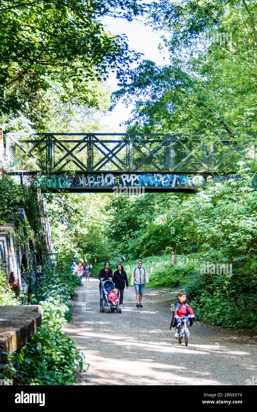 Wanderer genießen das warme Wetter auf dem Parkland Walk, einer stillgelegten Eisenbahnlinie, heute ein Naturschutzgebiet, in London, Großbritannien Stockfoto