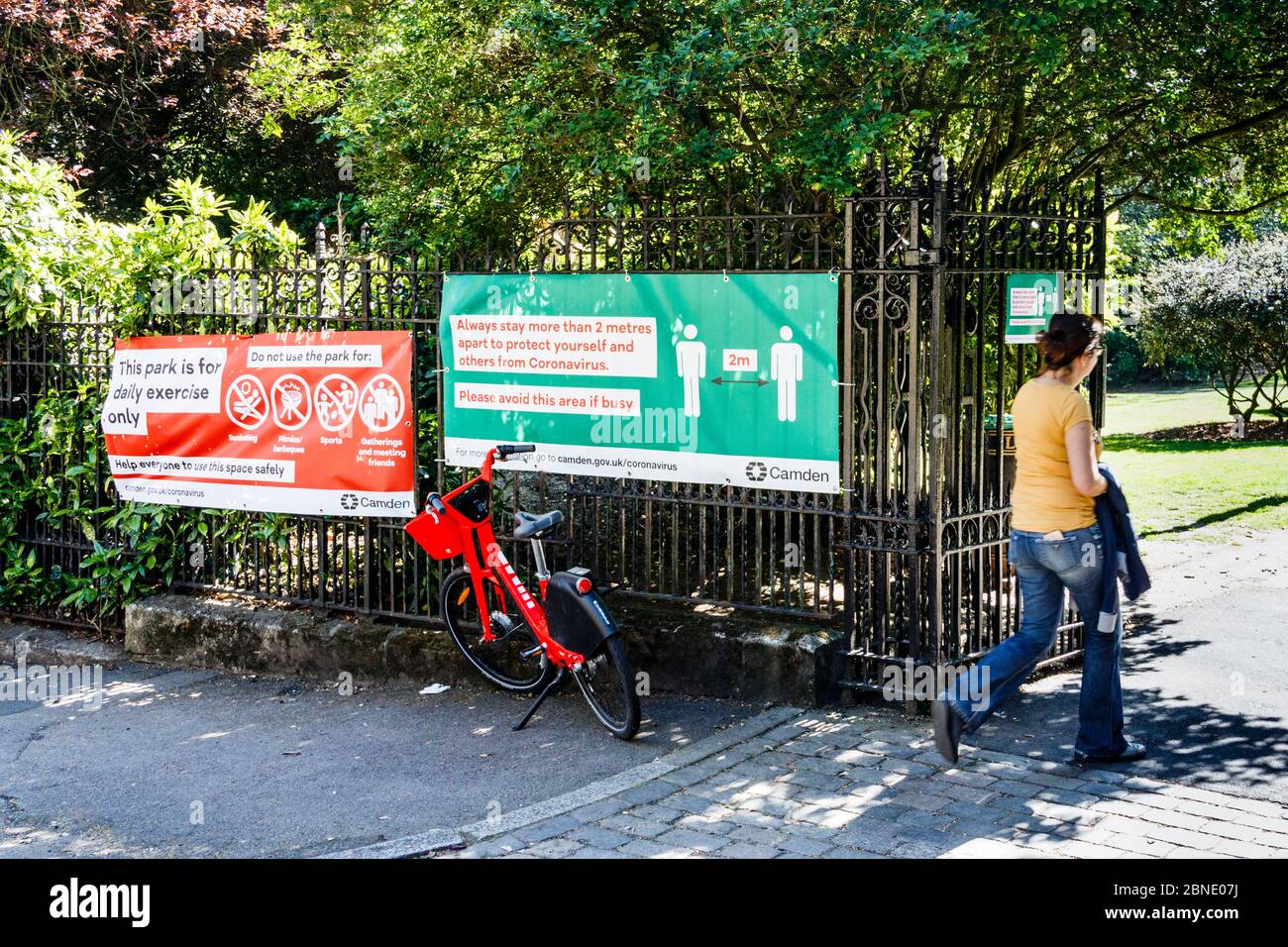 Eine Frau, die an einem sonnigen Tag während der Sperrung der Coronavirus-Pandemie einen Park zum Sport betritt, Rat zur sozialen Distanz vor den Toren Londons Stockfoto