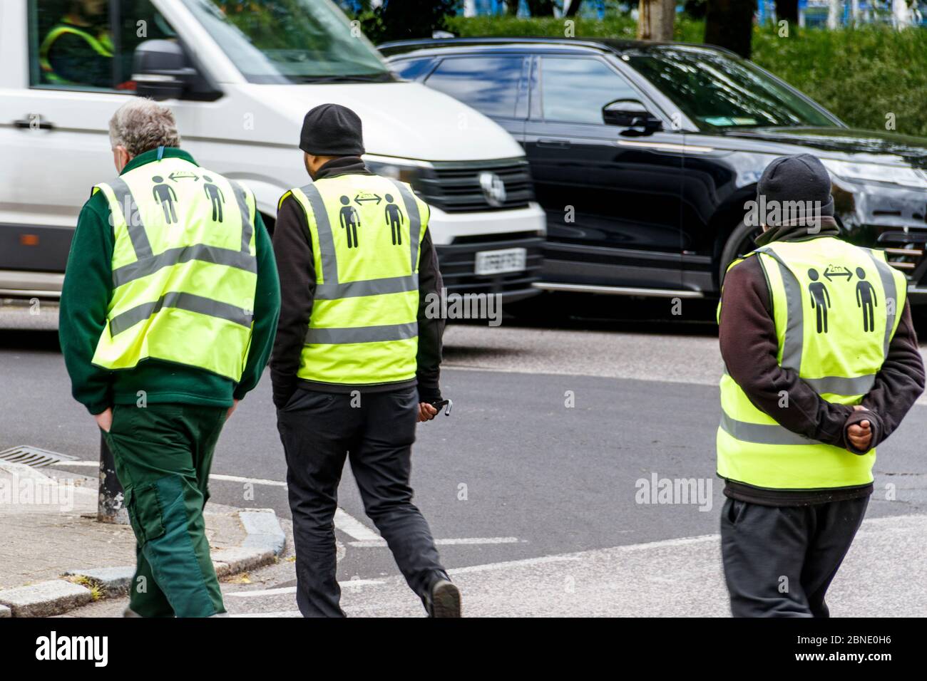 Drei ratsarbeiter ignorieren den sozialen Distanzierungstat, 2 Meter voneinander entfernt zu bleiben, geschrieben auf der Rückseite ihrer gut sichtbaren Jacken, London, Großbritannien Stockfoto
