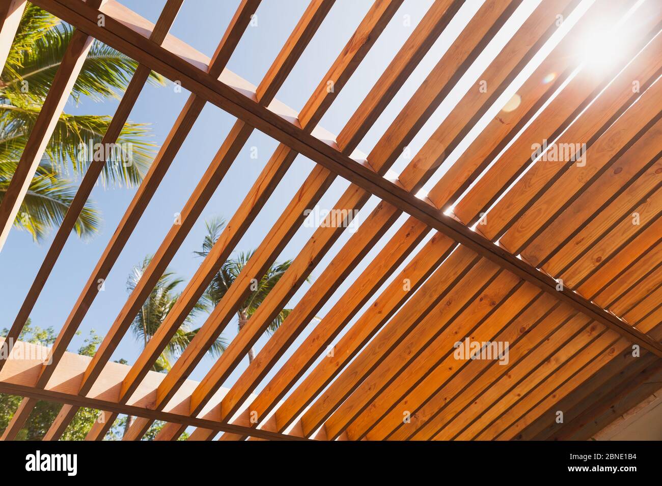 Hölzerne Sonnenschirm Dachstruktur unter blauem Himmel an sonnigen Sommertagen, Palmen sind auf einem Hintergrund Stockfoto