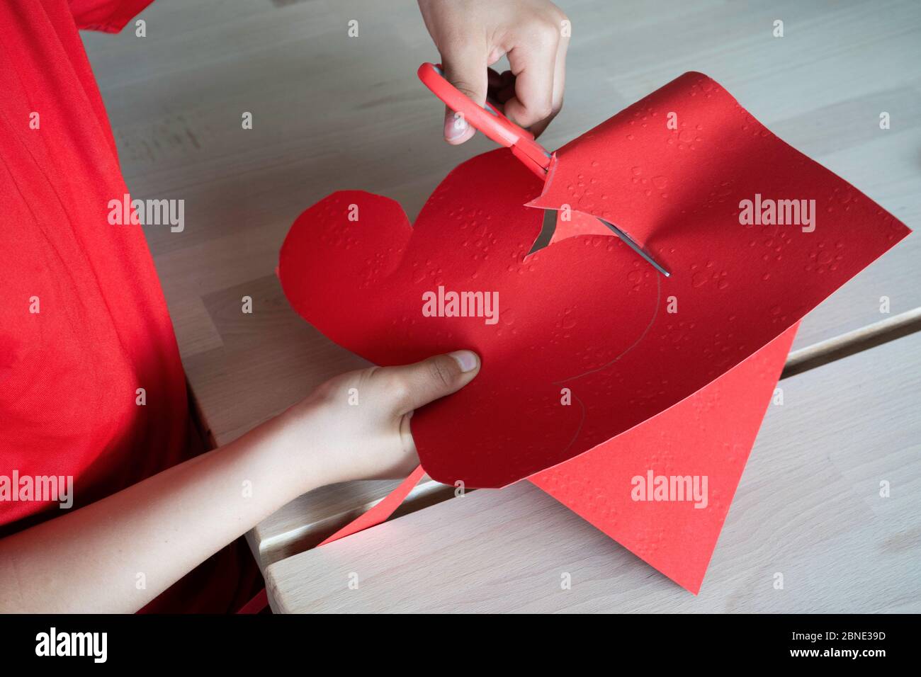 Kleiner Mann schneidet ein Herz - Geschenk für die Mutter Stockfoto