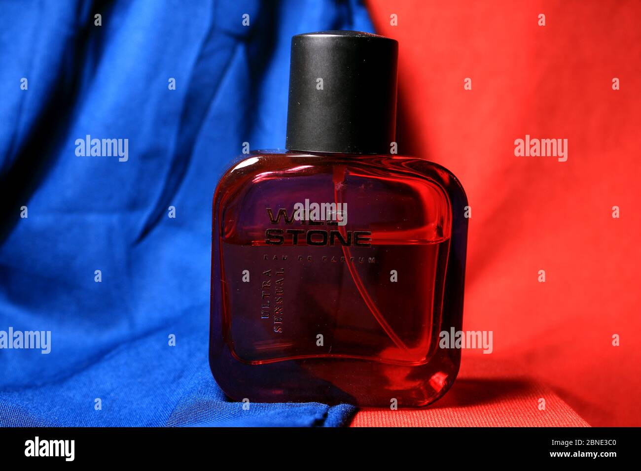 Rote Farbe Herren Parfüm Flasche isoliert auf blauem und rotem Hintergrund  mit weiblichen Accessoires. Rote Parfümflasche von 'Wild Stone' mit  schwarzer Kappe Stockfotografie - Alamy