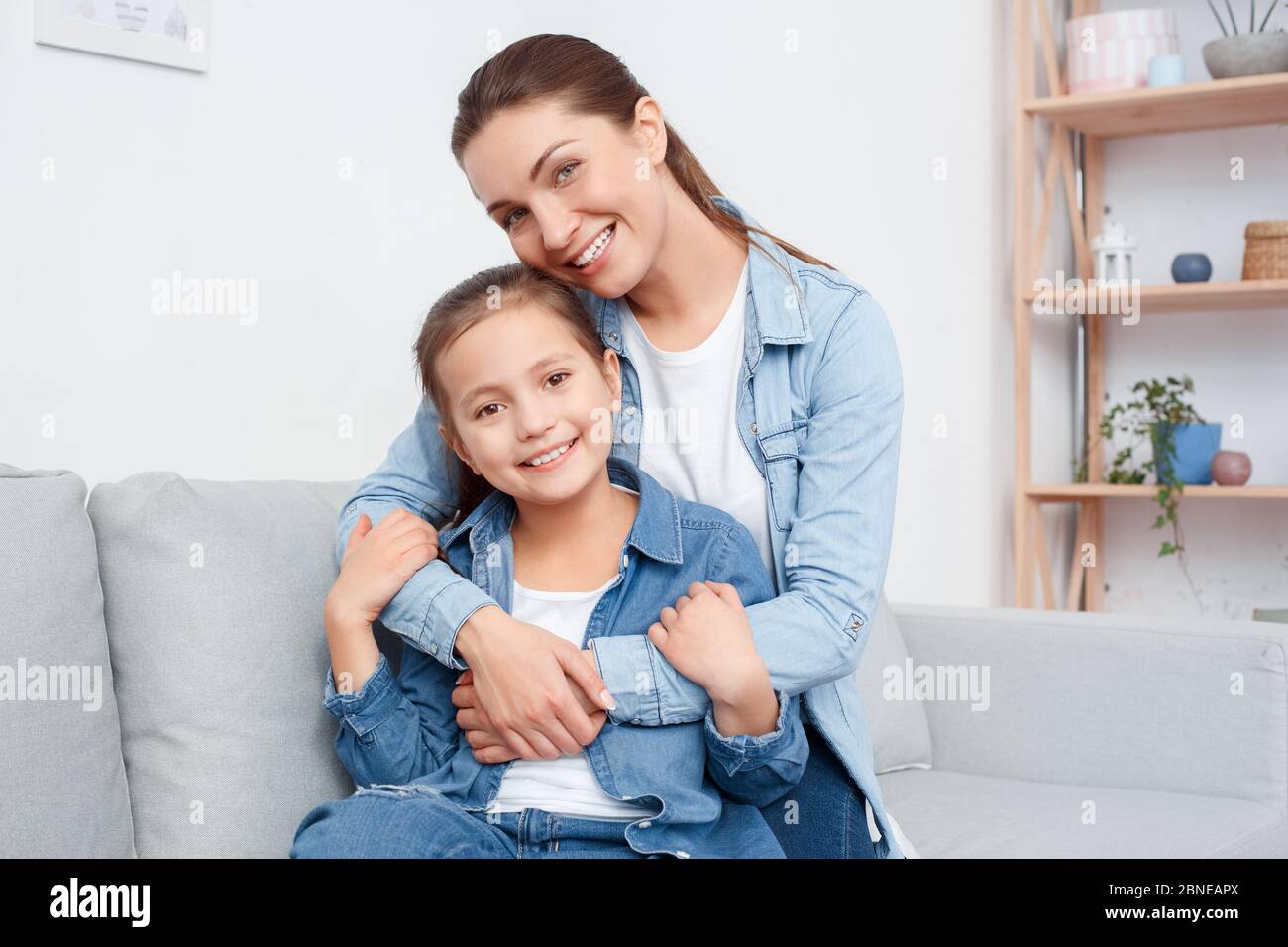 Junge Erwachsene Mutter mit ihrer lächelnden Tochter umarmt, verbringen Wochenende Tag zusammen Stockfoto