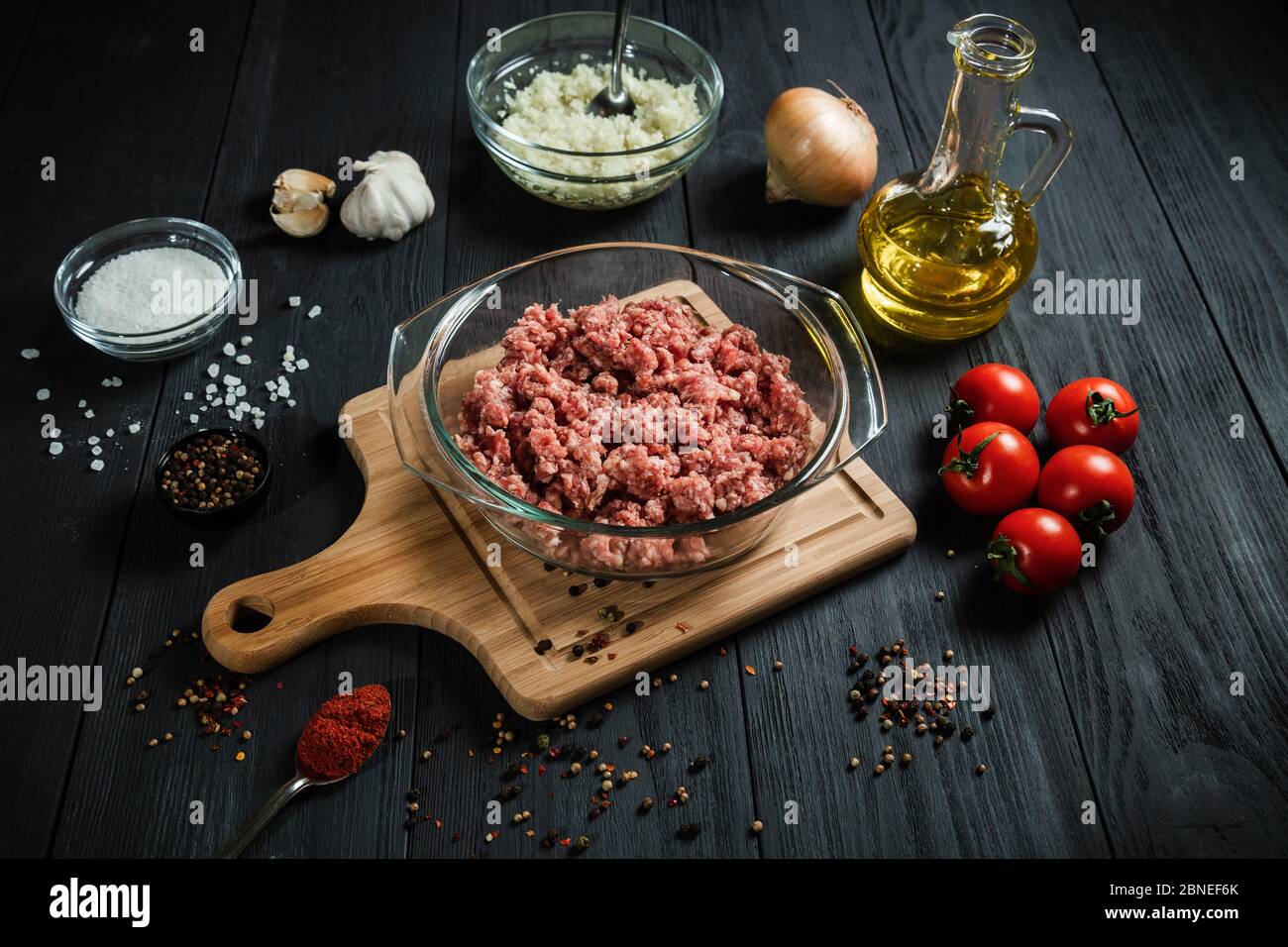 Rohes Hackfleisch mit Zutaten auf einem schwarzen Holztisch. Hausgemacht. Stockfoto