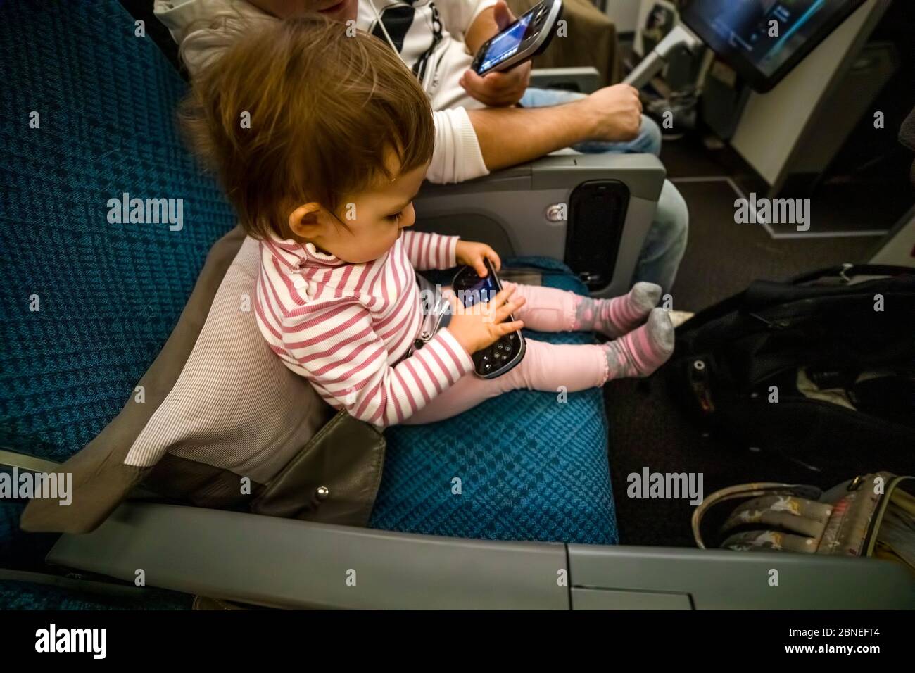 Unterhaltung an Bord des Flugzeugs. Kleinkind sitzen auf dem Flugzeug in den Sitz und spielen Spaß in der Multimedia-System Fernbedienung Stockfoto
