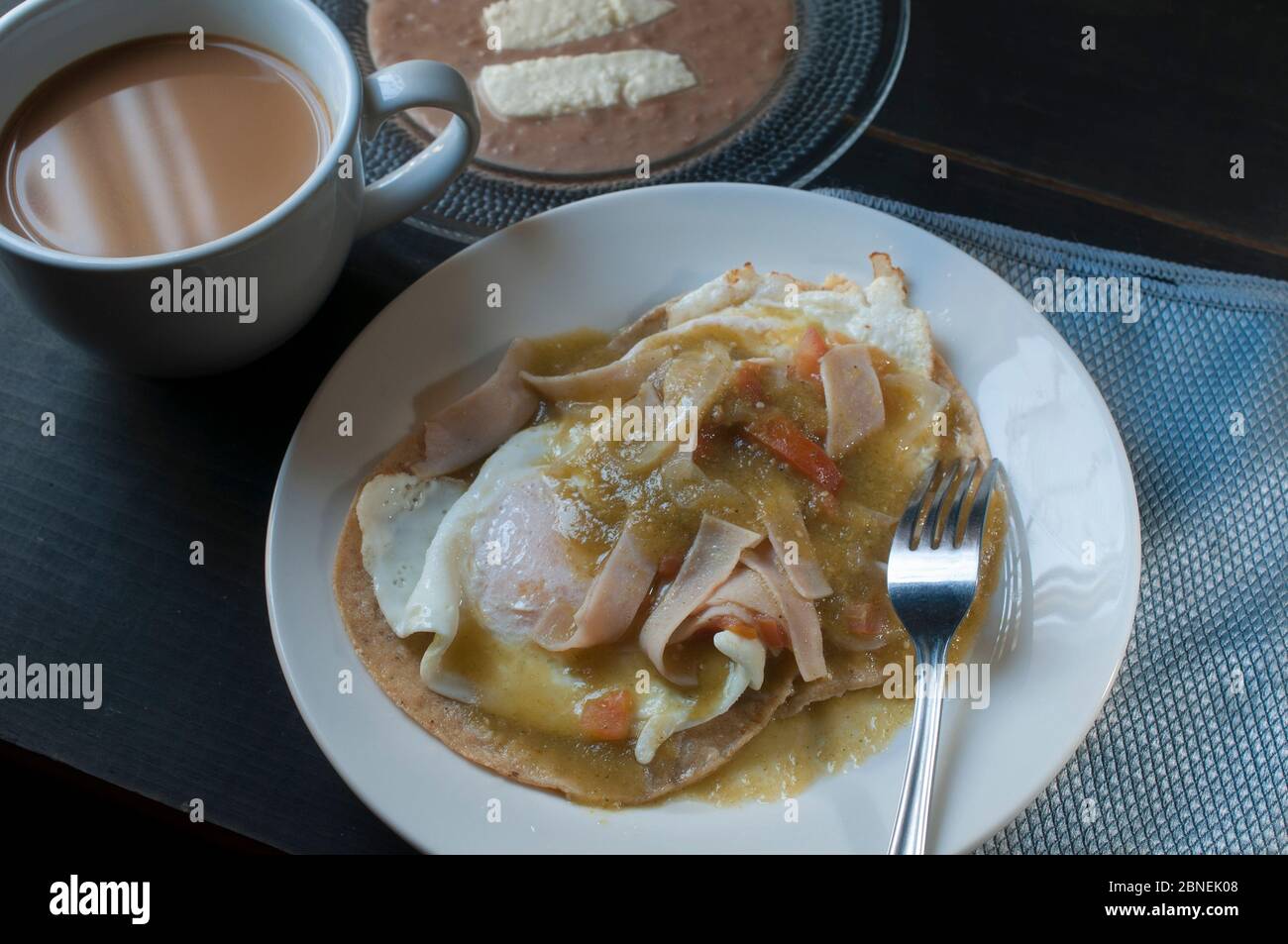 Seitenansicht von huevos Rancheros oder Ranch Eier mit gebratenen Bohnen, Ziegenkäse und Milchkaffee, mexikanisches Frühstück Konzept Stockfoto