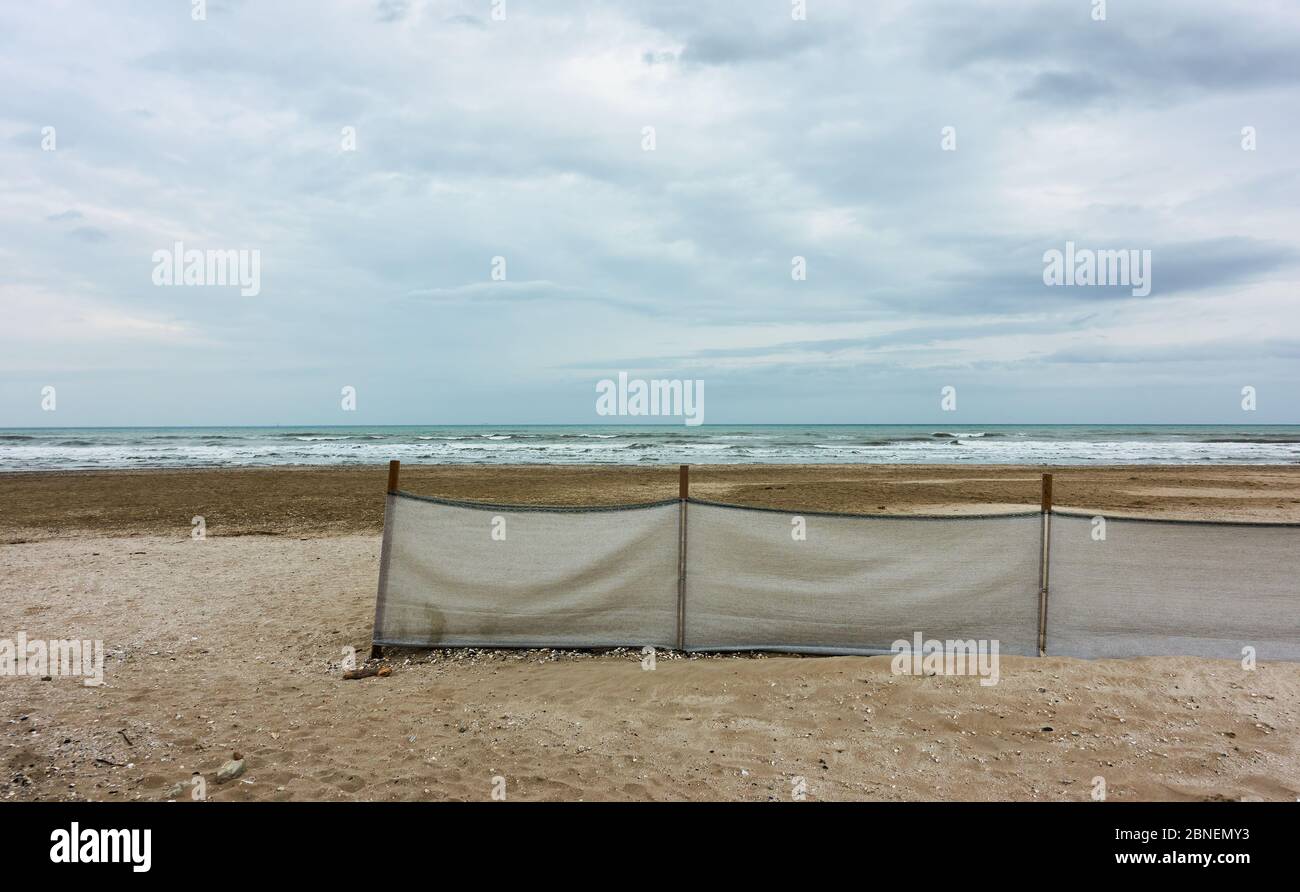 Sandstrand mit Stoffzaun in Rimini in der Nebensaison, Italien. Landschaft - Meereslandschaft Stockfoto