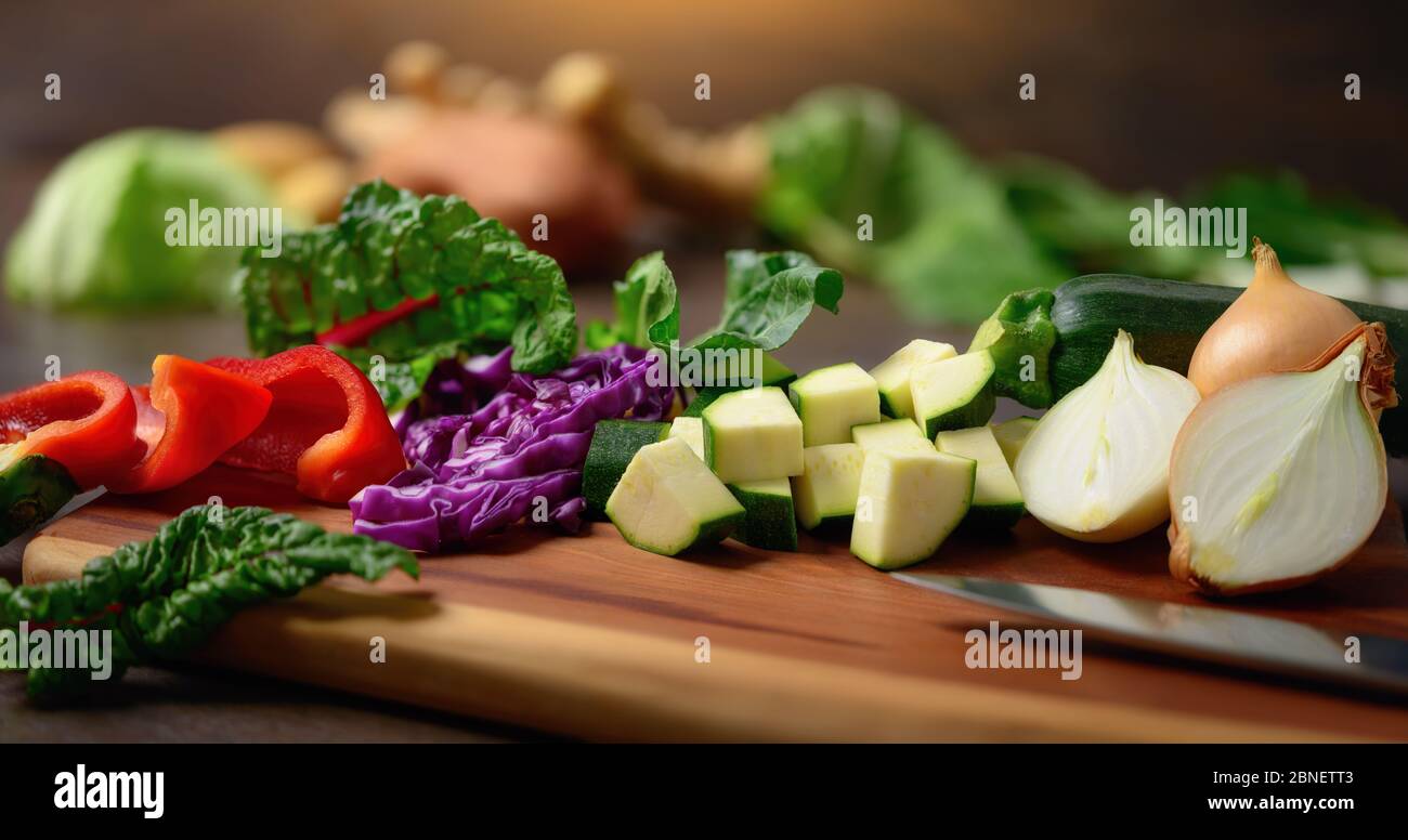 Kochen von Gemüse auf einem Holzbrett. Ein Nahaufnahme mit flachem Fokus zeigt bunte, nahrhafte und köstliche Zutaten als gesunde li Stockfoto