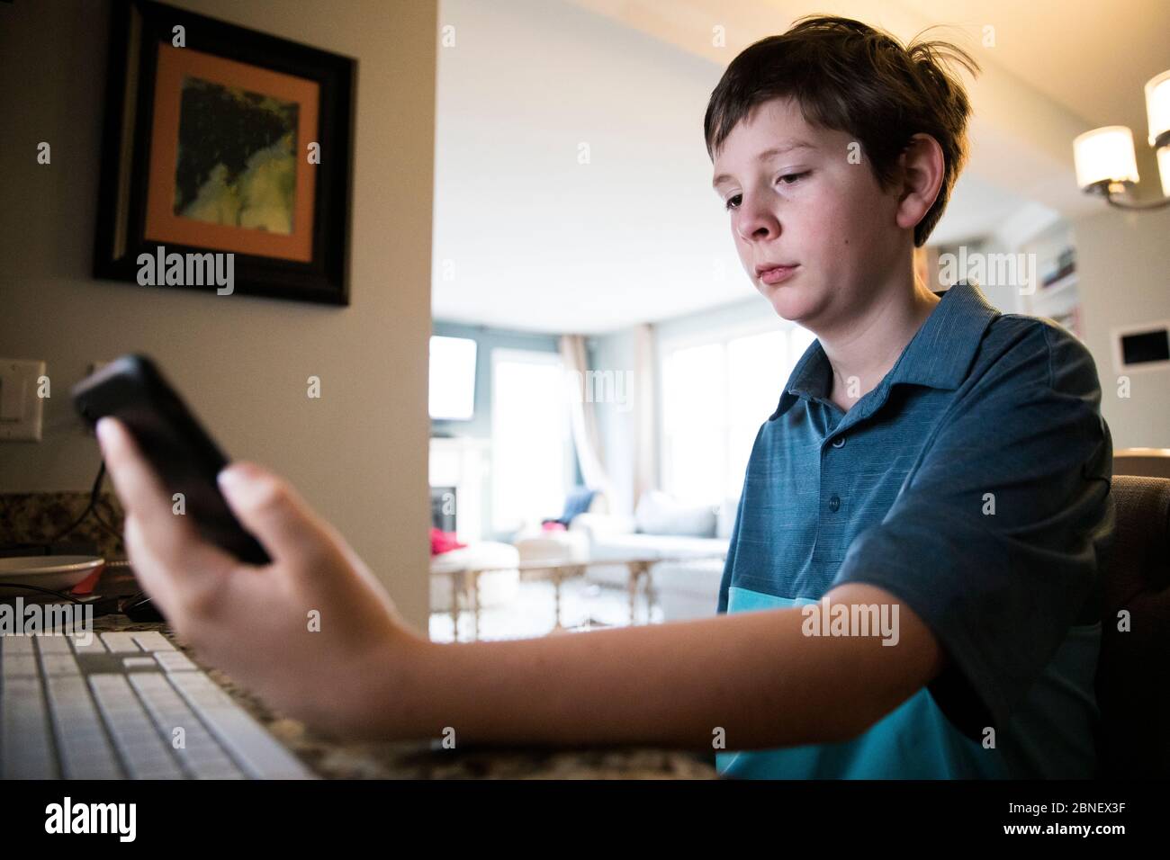 Niedrige Ansicht von Tween Boy am Computer Schreibtisch Texte lesen Auf dem iPhone Stockfoto