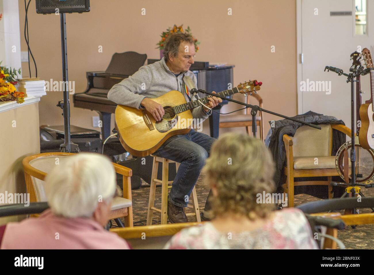 Foto von älteren männlichen, Gitarre spielen und singen, im Senior Center. Stockfoto