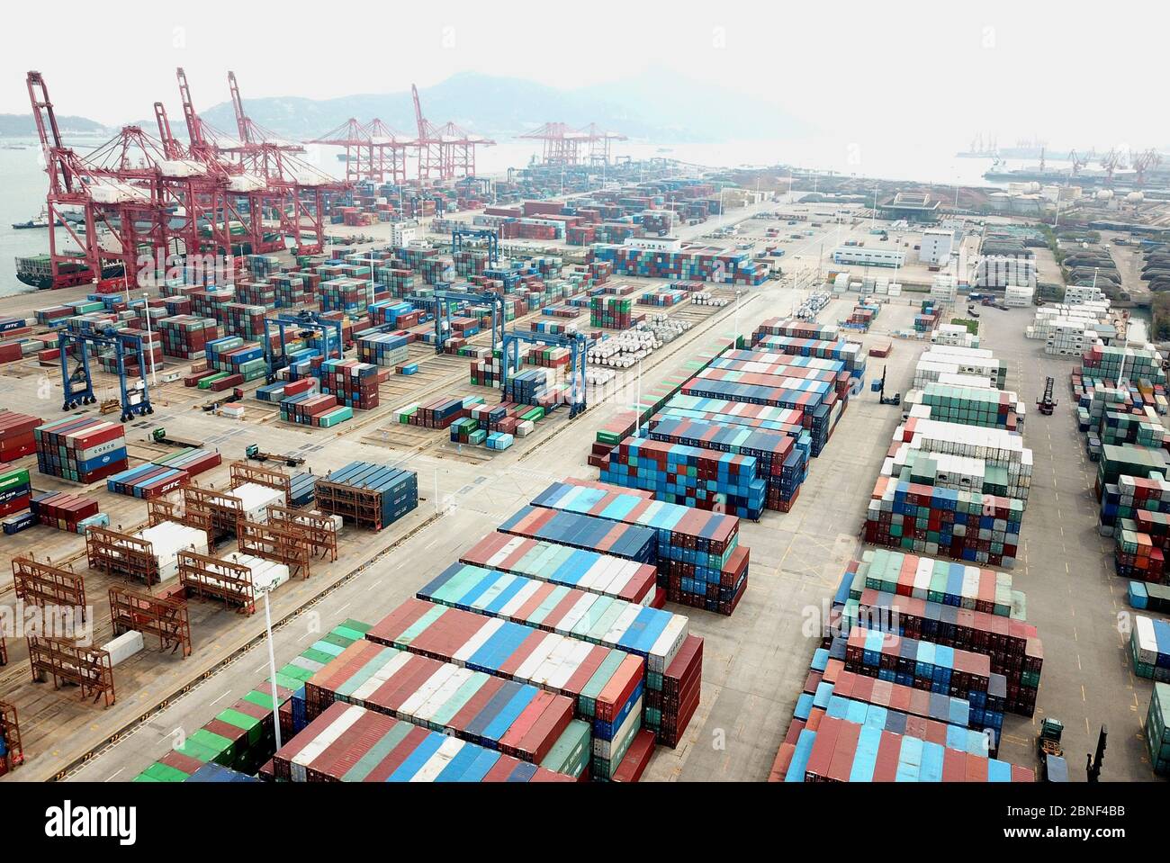 Lastwagen laden Container auf Schiffen, die Waren in einem Hafen in Lianyungang, Provinz Jiangsu, im Osten Chinas, nach Übersee exportieren, am 14. April 2020 Stockfoto