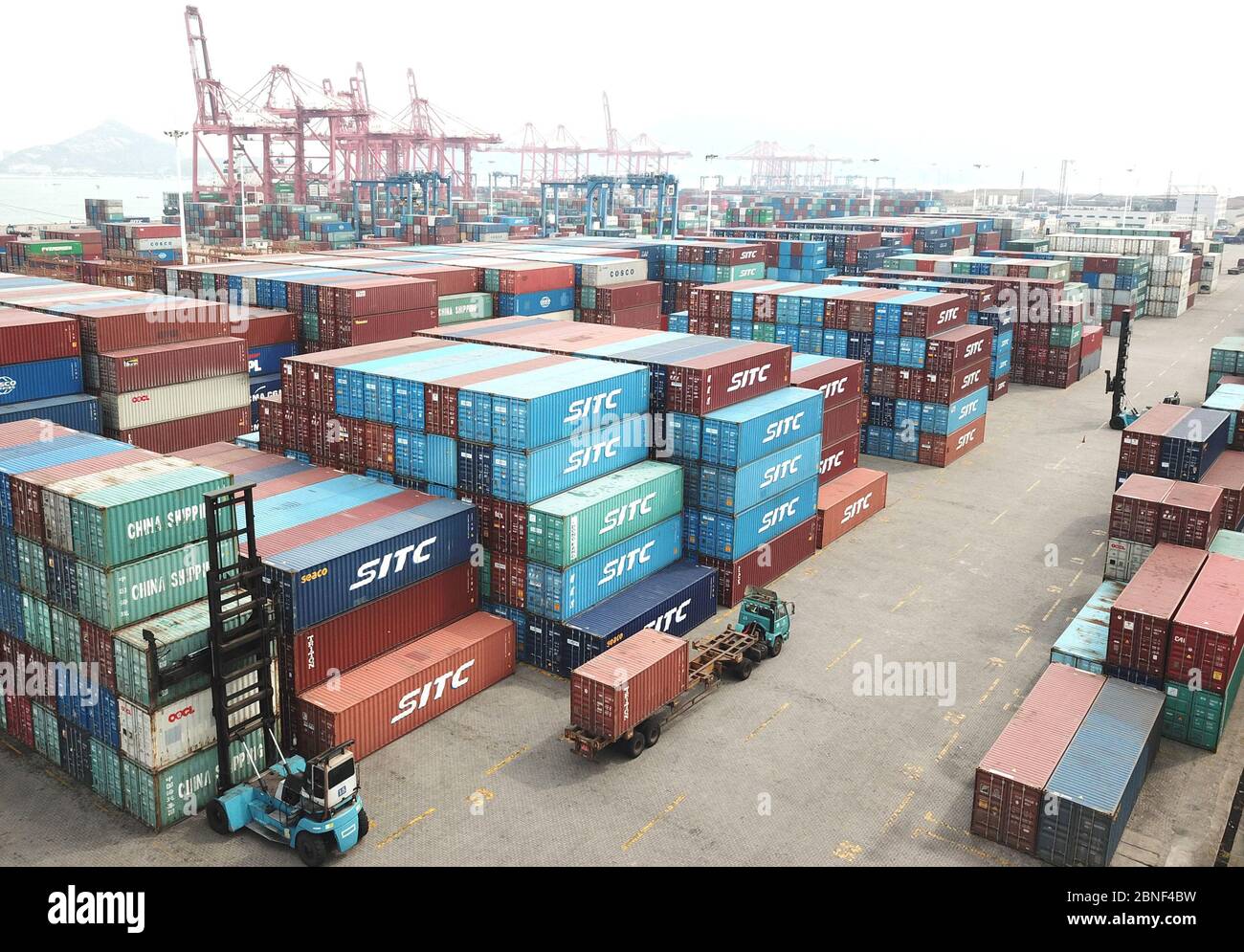 Lastwagen laden Container auf Schiffen, die Waren in einem Hafen in Lianyungang, Provinz Jiangsu, im Osten Chinas, nach Übersee exportieren, am 14. April 2020 Stockfoto