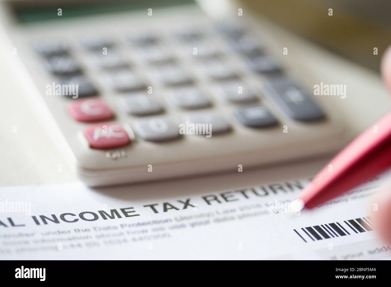 Eine Person, die ein persönliches Einkommensteuererklärung Formular ausfüllt. Stockfoto