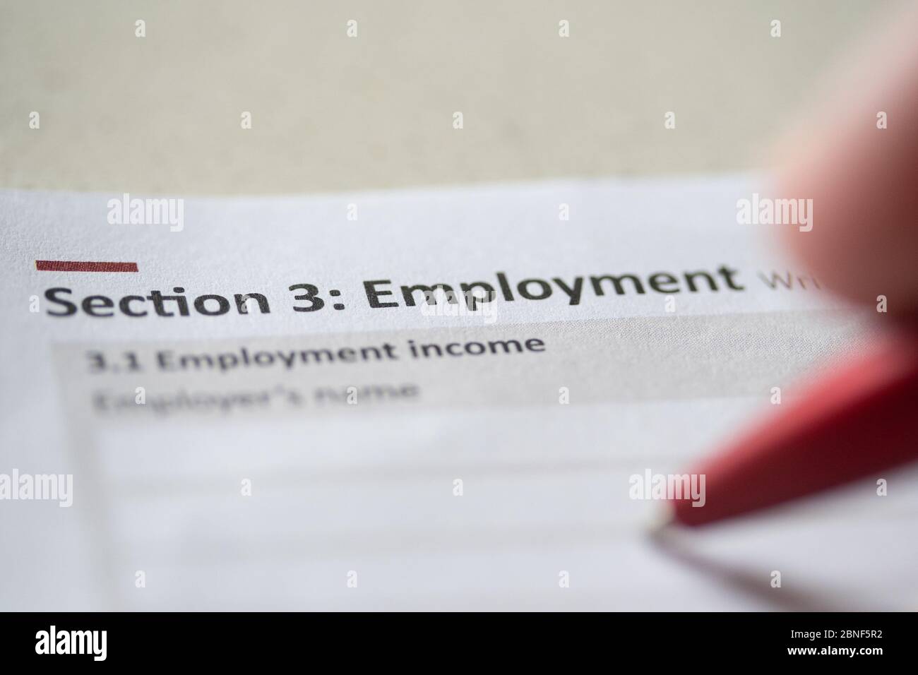 Eine Person, die Angaben zu den Einkünften in einem Einkommensteuerformular ausfüllt Stockfoto