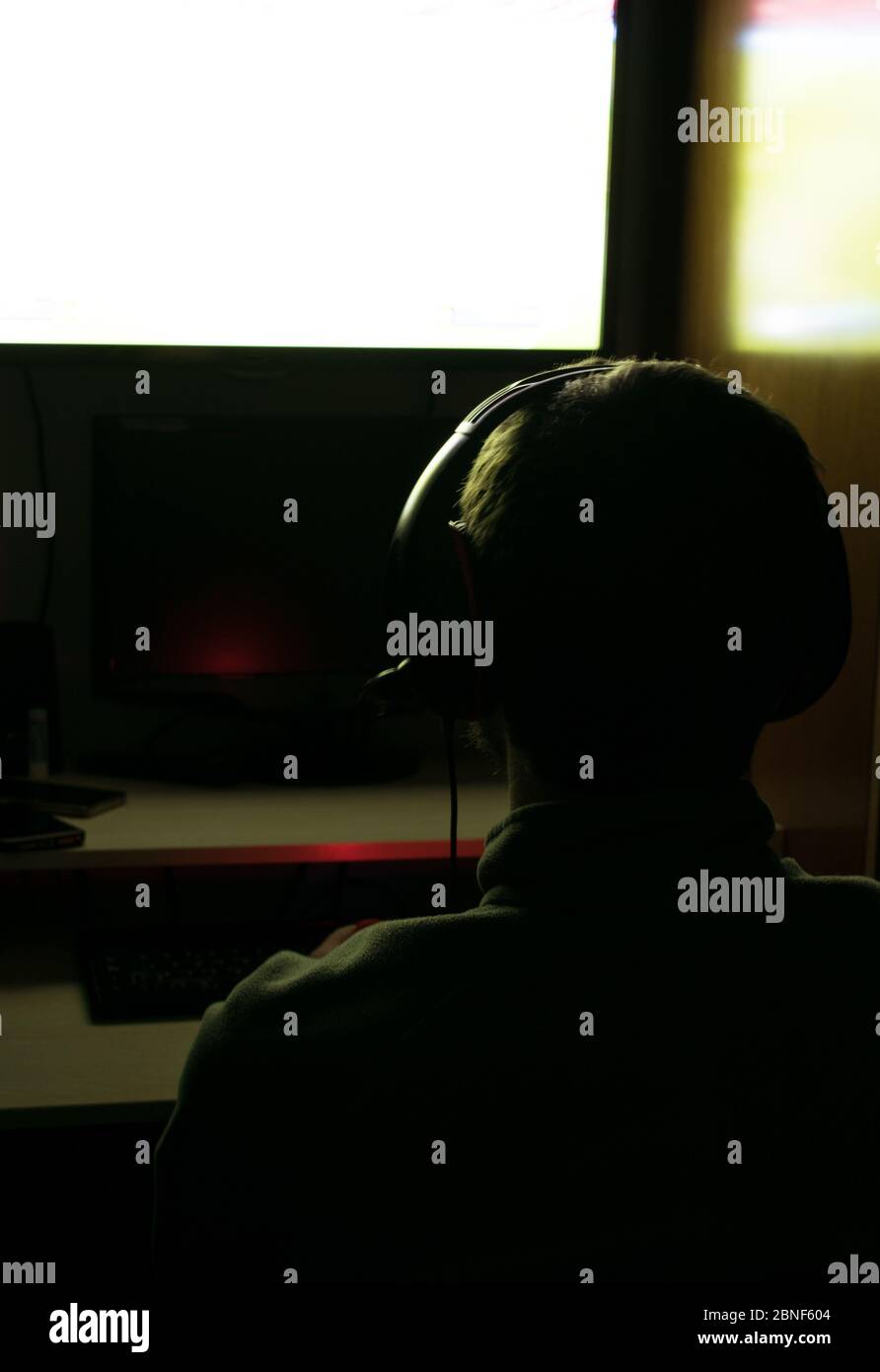 Rückansicht eines Mannes, der Videospiele mit Kopfhörern spielt Stockfoto