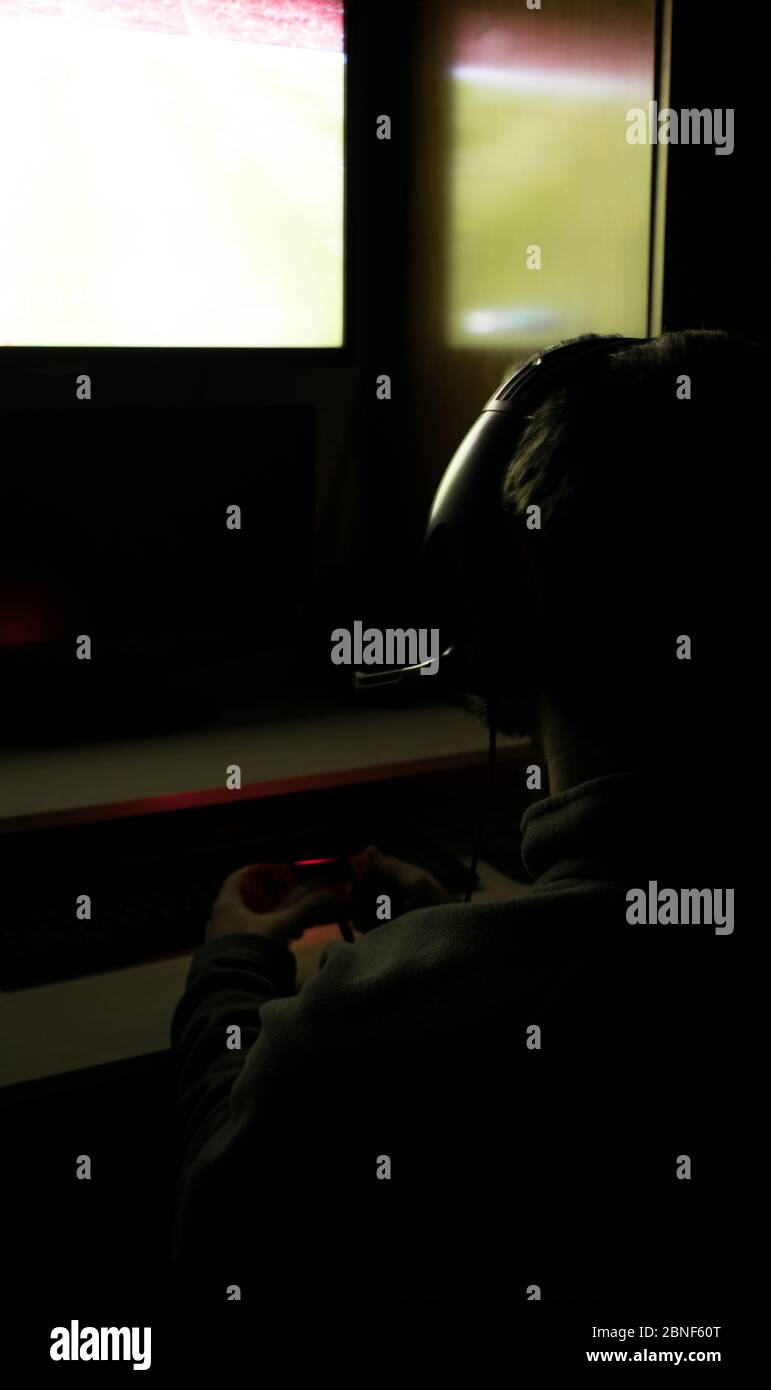 Rückansicht eines Mannes, der Videospiele in seinem spielt Schlafzimmer mit dem l Stockfoto