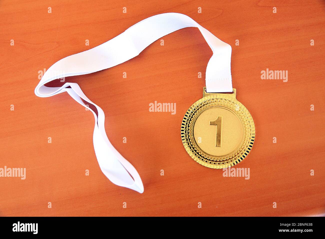 Goldmedaille im Vordergrund auf weißem Band. Goldmedaille auf gelbem Hintergrund mit leerem Gesicht für Text. Stockfoto