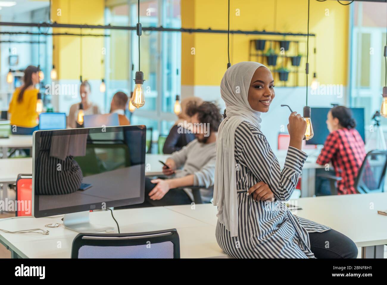 Trait einer schwarzen (afroamerikanischen) weiblichen muslimin, die in einem modernen Geschäftsbüro steht, während sie einen Hijab trägt. Stockfoto