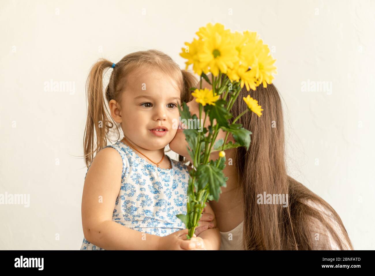 Mutterschaft, Muttertag, Geburtstag, Kindheit, Familienkonzept - close-up kleines Mädchen in der Kleidung gratulieren und geben junge Mutter Bouquet von gelb Stockfoto