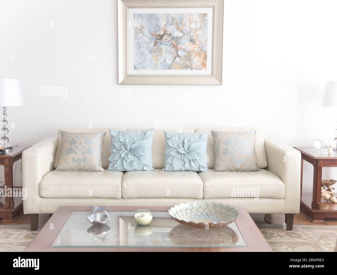 Wohnzimmer mit weißem Sofa, Couchtisch und Gemälde an der Wand Stockfoto