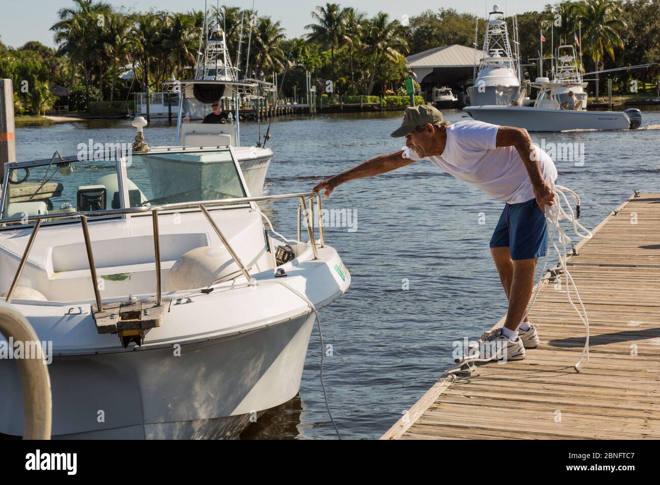 Ein Mann versucht, sein Treibboot an einen Pier im Sandsprit Park in Port Salerno, Florida, USA anzudocken. Stockfoto