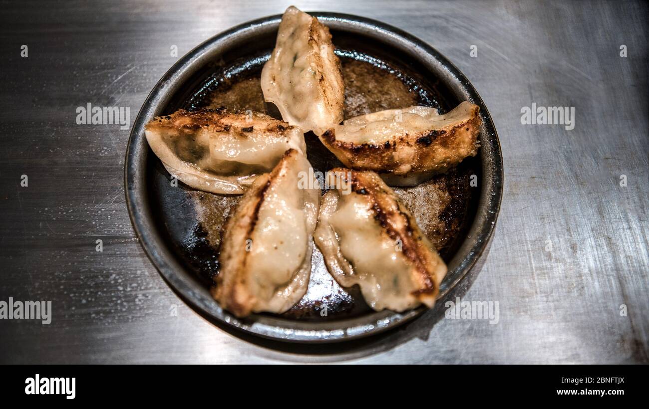 Gebratene Knödel in einem Restaurant. Guotie ist ein traditionelles japanisches Essen. Portionen köstlicher Gyoza auf dem Metalltisch serviert. Stockfoto
