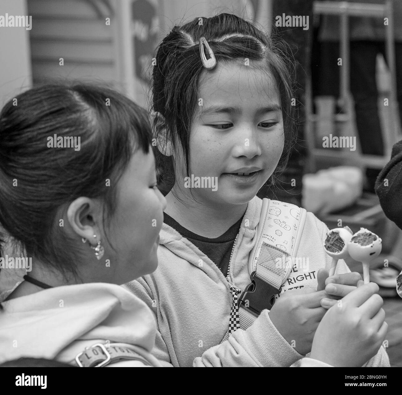 Zwei Mädchen genießen ein Bonbon, das sie gerade in der Takeshita Straße, Harajuku, Tokyo, Japan gekauft haben Stockfoto