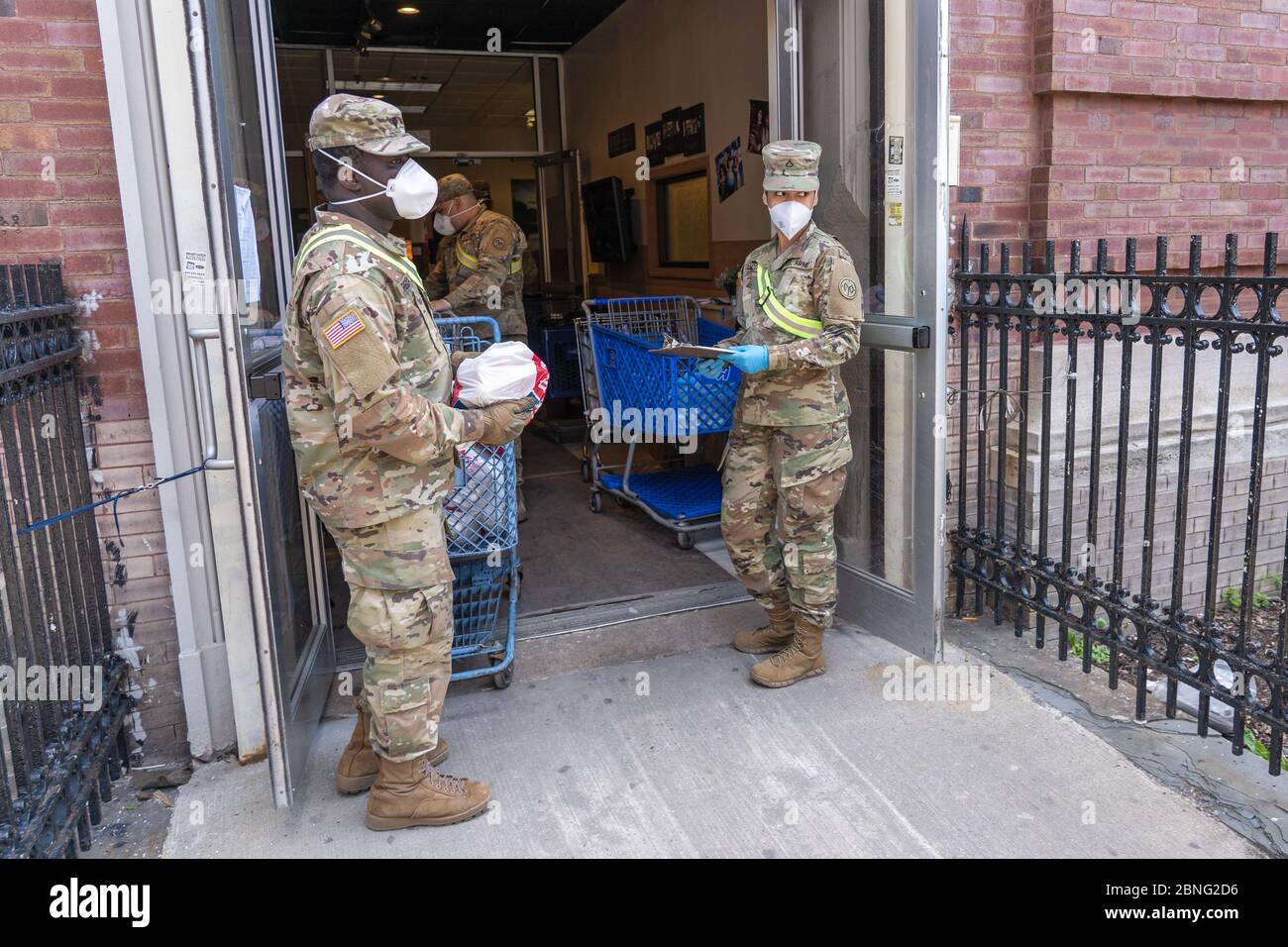 New York, Usa. Mai 2020. Mitglieder der US Army National Guard tragen Beutel mit Lebensmitteln und anderen wichtigen Dingen, die an Bedürftige in einer Speisekammer inmitten der Coronavirus-Pandemie (Covid-19) im Stadtteil Queens in New York City verteilt werden. Quelle: SOPA Images Limited/Alamy Live News Stockfoto