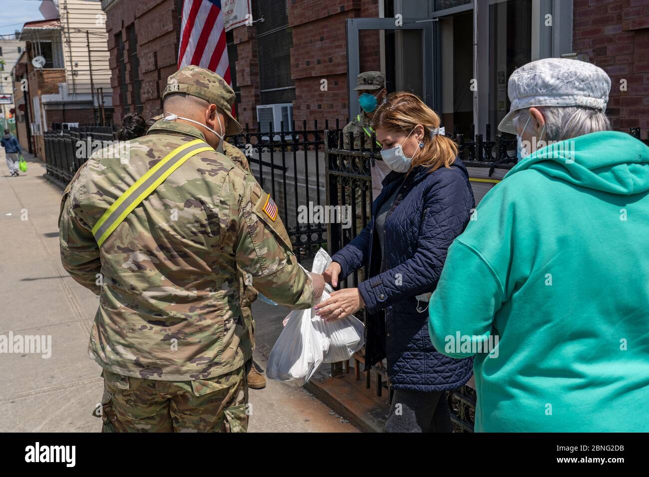 New York, Usa. Mai 2020. Eine Frau erhält Nahrung und andere wichtige Dinge von einem Mitglied der US Army National Guard in einer Speisekammer inmitten der Coronavirus-Pandemie (Covid-19) im Stadtteil Queens in New York City. Quelle: SOPA Images Limited/Alamy Live News Stockfoto