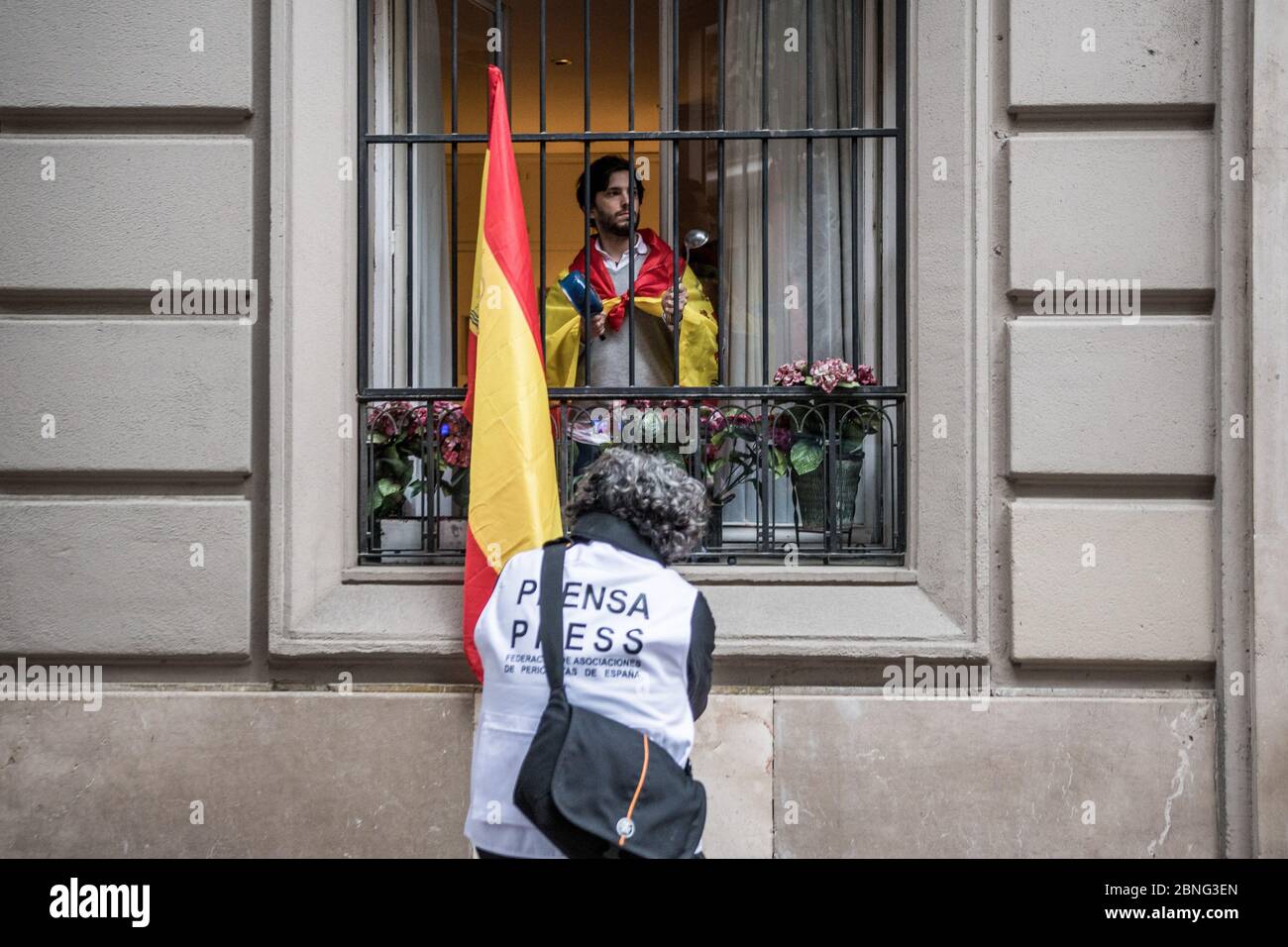 Madrid, Spanien. Mai 2020. Ein Pressefotograf fotografiert einen Mann, der während der Demonstration in eine Flagge auf seinem Fenster gehüllt ist. Die Bewohner des gehobenen Viertels Salamanca protestieren gegen die Regierungsführung der Coronavirus-Krise. Einige Teile Spaniens haben seit ihrer Coronavirus-Blockade den Übergang in die Phase 1 aufgenommen, so dass viele Geschäfte und Restaurants, die Outdoor-Kunden bedienen, wieder geöffnet werden können. Die am stärksten von der Covid-19 betroffenen Orte wie Madrid und Barcelona befinden sich jedoch weiterhin in einer strengeren Phase-0-Quarantäne. Quelle: SOPA Images Limited/Alamy Live News Stockfoto