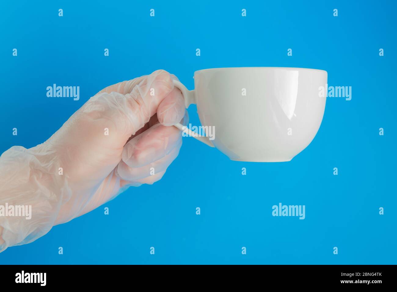 Arzthand in medizinischen Handschuh hält die weiße Teetasse Stockfoto