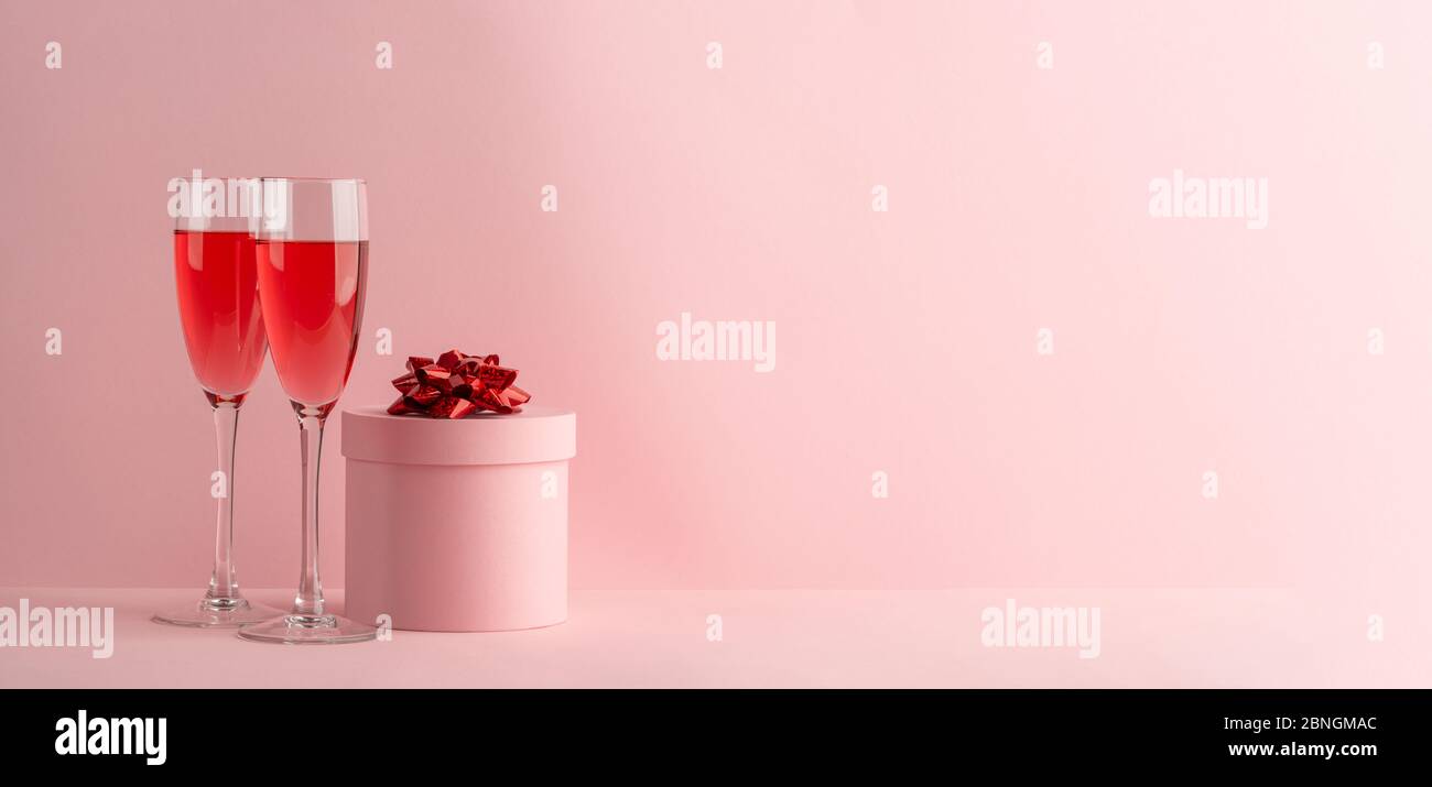 Zwei Gläser roter Prosecco und Valentinstag Geschenk auf rosa Hintergrund Stockfoto