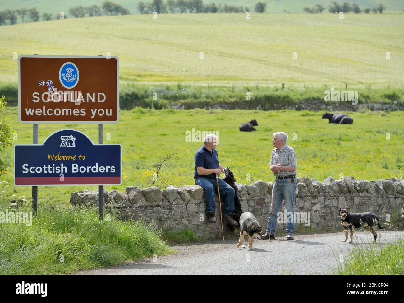 Zwei bäuerliche Nachbarn, ein Schotte (links) und der andere Engländer unterhalten sich an der England-Schottland-Grenze bei Kirk Yetholm. Stockfoto