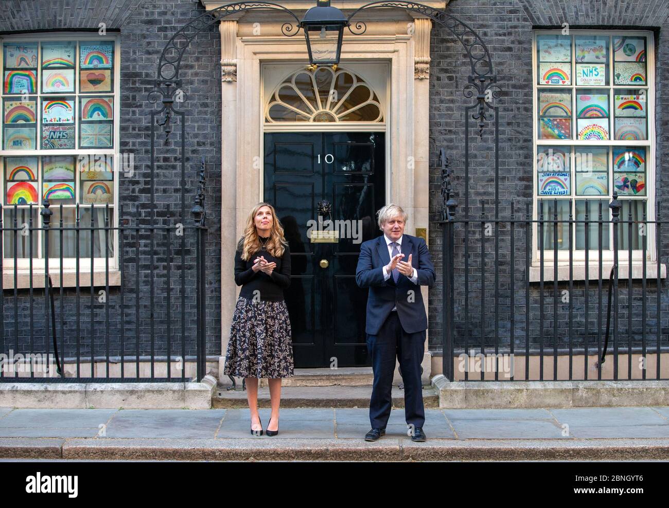 Premierminister Boris Johnson wird auf den Stufen der Downing Street 10 von Verlobter Carrie Symonds begleitet, um "Clap for Carers" zur Unterstützung des NHS zu unterstützen. Stockfoto