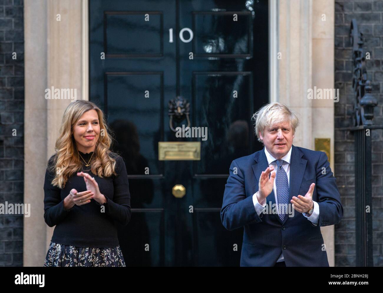 Premierminister Boris Johnson wird auf den Stufen der Downing Street 10 von Verlobter Carrie Symonds begleitet, um "Clap for Carers" zur Unterstützung des NHS zu unterstützen. Stockfoto