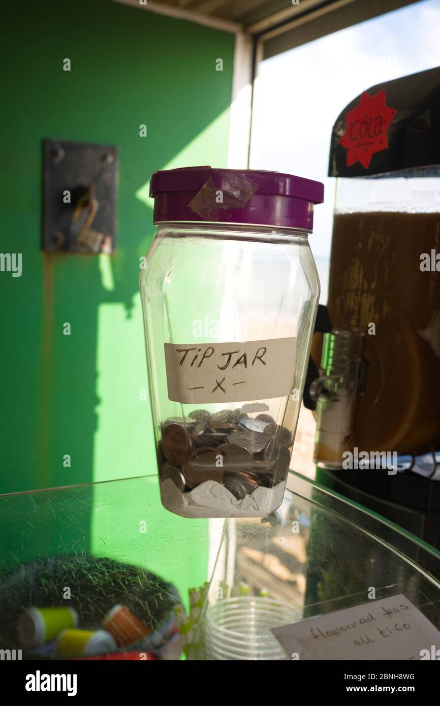 Nahaufnahme eines Glas-Tipp-Glas mit Münzen auf der Theke einer Snack-Bar am Strand in der Nähe von Lyme Regis, Großbritannien Stockfoto