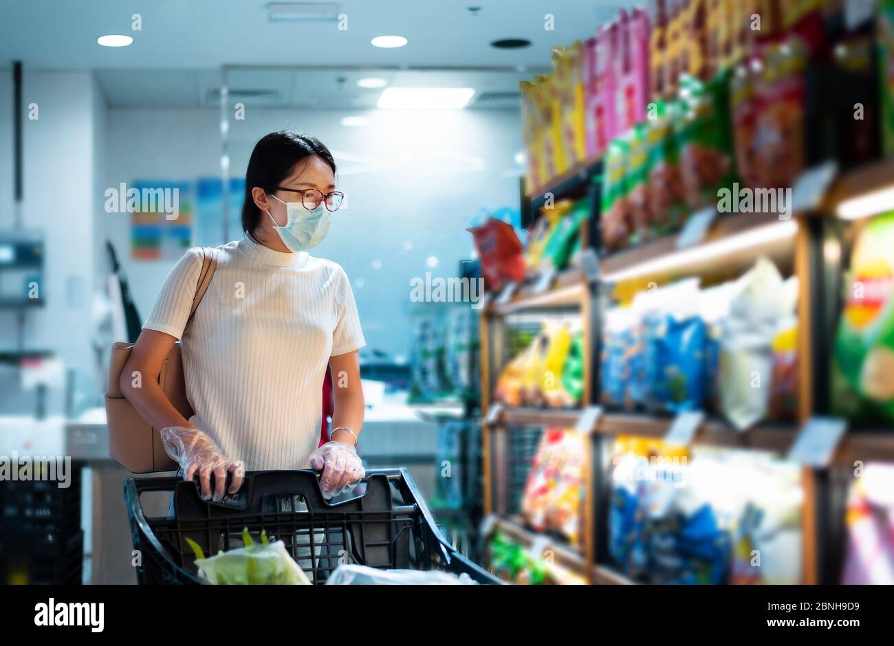 Asiatische Frau, die auf dem Markt Lebensmittel kauft, trägt Maske und Handschuhe, um die Ausbreitung von Virius während der Coronavirus-Pandemie zu verhindern Stockfoto