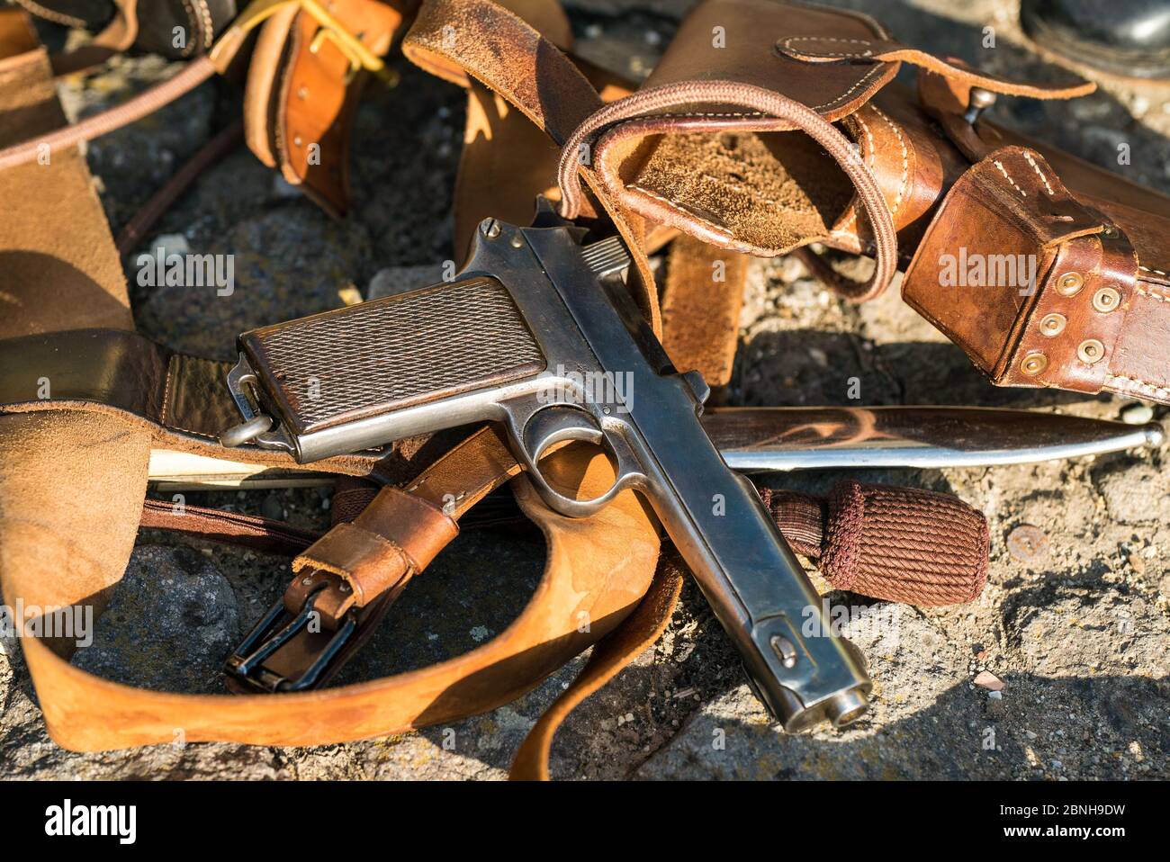 Pistole aus dem Ersten Weltkrieg und genähte Niettaschen aus Leder auf dem Stein der Straße platziert. Stockfoto